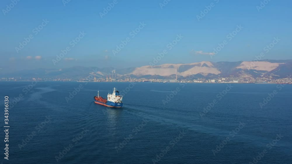 Aerial view following the ultra large cargo ship at sea leaves port at sunset Aerial view following the ultra large cargo ship at sea leaves port at sunset