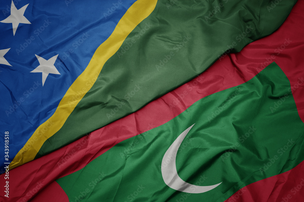waving colorful flag of maldives and national flag of Solomon Islands .