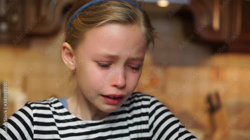 Blond child girl crying heavily tears drop down her face offended in home kitchen. Child abuse bad childhood Blond child girl crying heavily tears drop down her face offended in home kitchen. Child abuse bad childhood