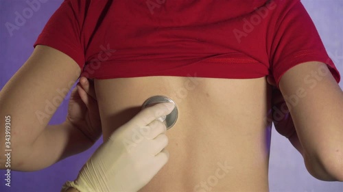 Close up of doctor examining school boy patient with a stethoscope for diagnostic sars or coronavirus. Stop dangerous COVID-19 infection photo