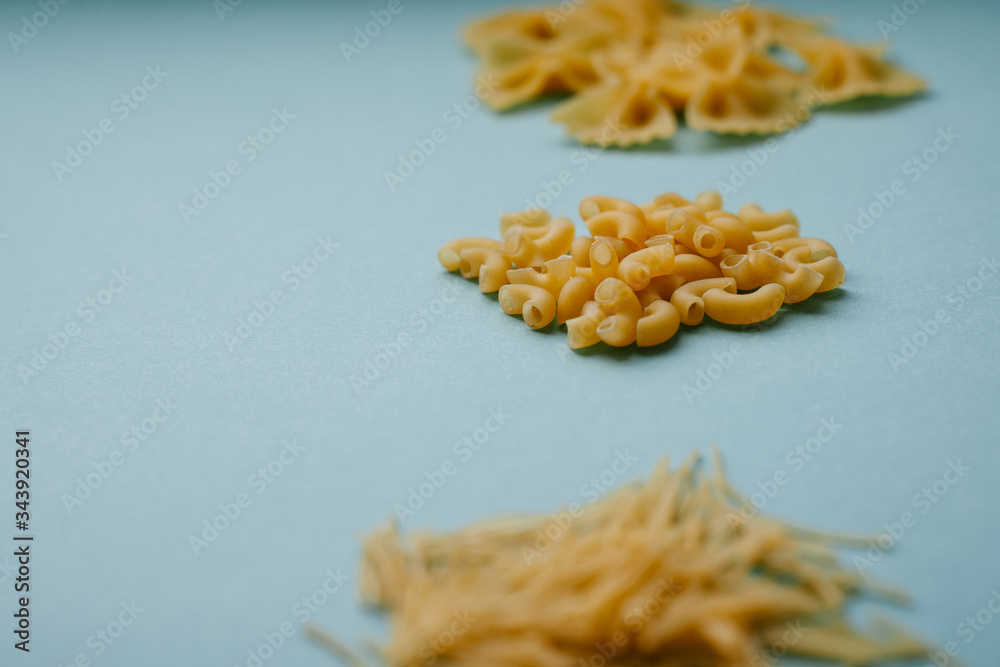 Close-up of pasta horns on a blue background. Blur wheat flour products. Types of Italian pasta.Background. Close-up of pasta horns on a blue background. Blur wheat flour products. Types of Italian pasta.Background.