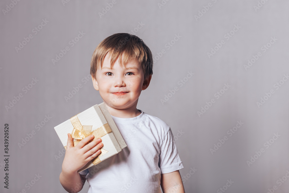 Beautiful little boy in a white T-shirt holding a gift in his hand, mother's day, Valentine's day, March 8, birthday Beautiful little boy in a white T-shirt holding a gift in his hand, mother's day, Valentine's day, March 8, birthday
