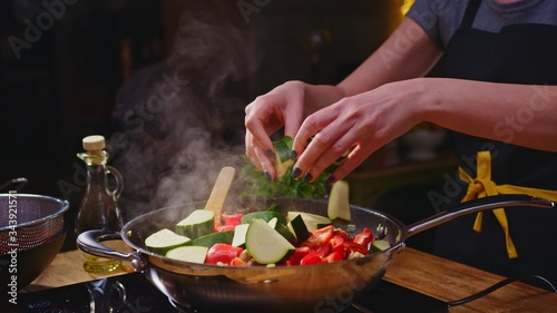 Woman cooking frying in kitchen in wok pan