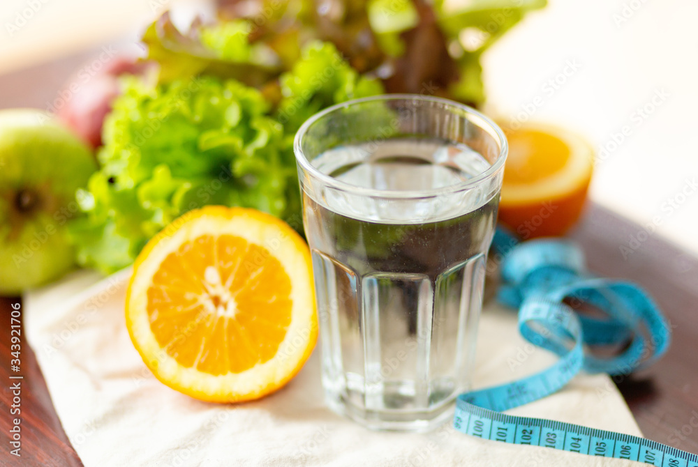 Fototapeta premium healthy eating, drinks, measuring blue tape, diet, detox and people concept - close up fruit water in glass