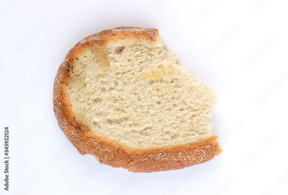 Bitten piece of bread isolated on white background. Dry slice from a white loaf. View from above