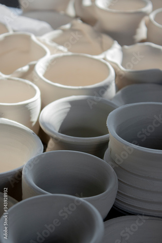 Handicraft production of clay pots. Handmade ceramics before firing. A lot of dishes from clay on the table. Close-up, perspective view