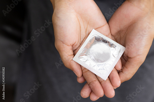 Woman hand holding and condom sitting on sofa background,protection, safe sex,contraceptive means.
