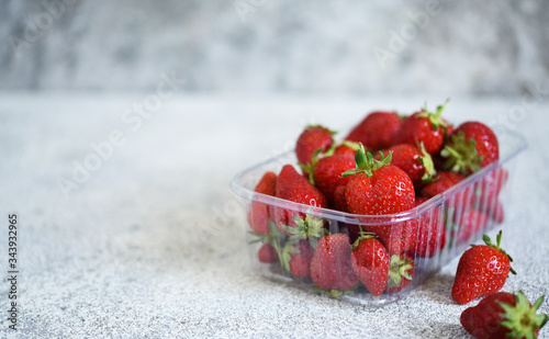 Strawberries in a tray on a concrete gray background with place for text. Horizontal focus.