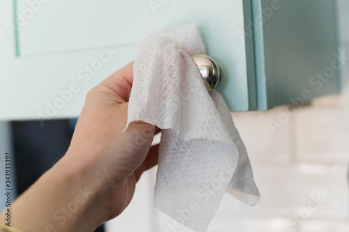 Close-up of hand wiping down knob with disinfectant