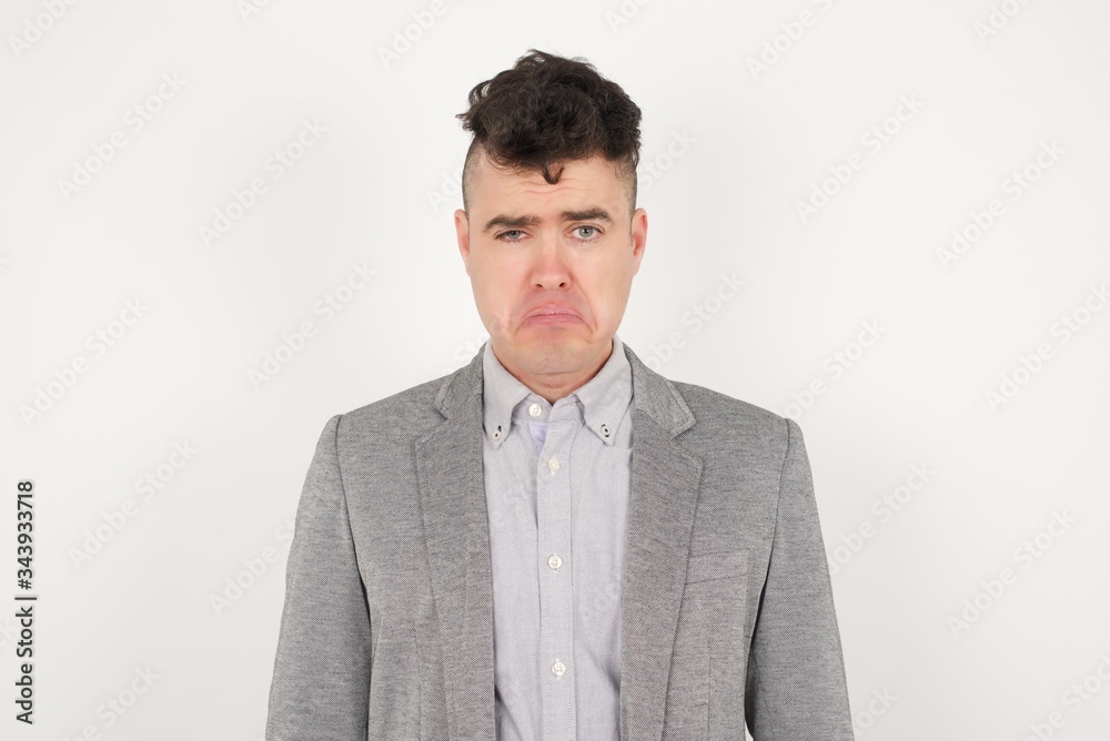 Beautiful face of sad man crying desperate and depressed with tears on his eyes suffering pain and depression isolated on grey background in sadness facial expression and emotion concept. Beautiful face of sad man crying desperate and depressed with tears on his eyes suffering pain and depression isolated on grey background in sadness facial expression and emotion concept.