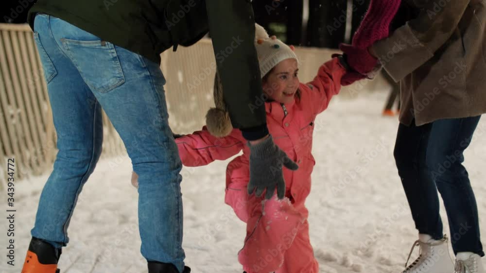 christmas, family and leisure concept - happy mother and father helping little daughter to rise up at outdoor skating rink in winter christmas, family and leisure concept - happy mother and father helping little daughter to rise up at outdoor skating rink in winter