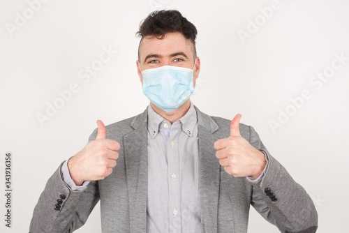 Closeup of young optimistic male isolated on grey background showing thumbs up with positive emotions of content and happiness. Copyspace, concept of satisfaction with quality and recommendation.