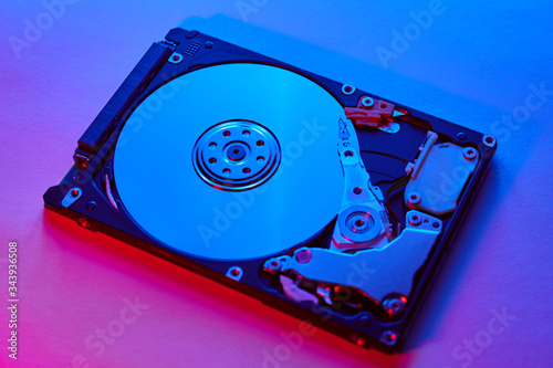 Disassembled hard drive from the computer, hdd with neon light. Opened hard drive Part of computer or laptop photo