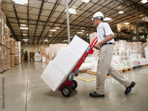 Man pushing hand truck in warehouse photo