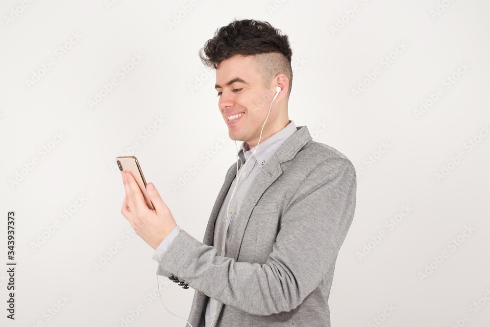 Handsome Caucasian businessman watching something funny or having a pleasant phone conversation, listening through his earphones. Handsome Caucasian businessman watching something funny or having a pleasant phone conversation, listening through his earphones.