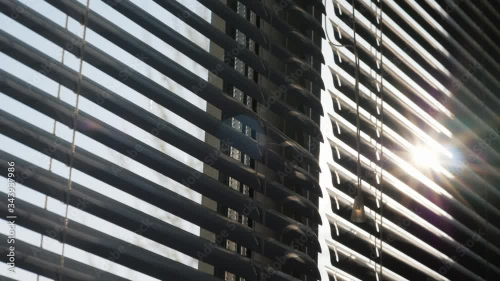 Tilt shot: The sun shines through the blinds on the window Tilt shot: The sun shines through the blinds on the window