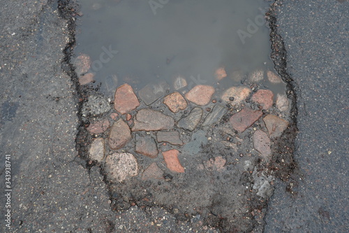 Pot hole revealing old stone road below modern asphalt. 