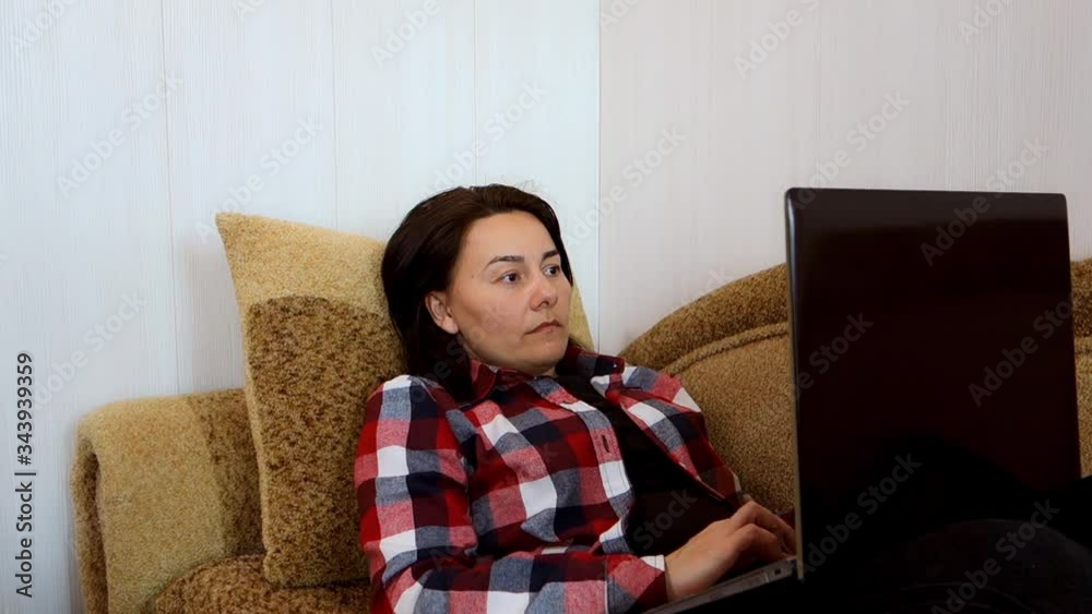 Caucasian pretty woman working as a freelancer on the couch in the living room on the laptop computer. Caucasian pretty woman working as a freelancer on the couch in the living room on the laptop computer.