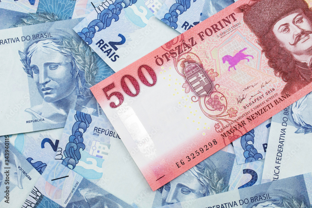 Obraz premium A close up image of a red Hungarian five hundred forint bank note with Brazilian two reais bank notes in the background