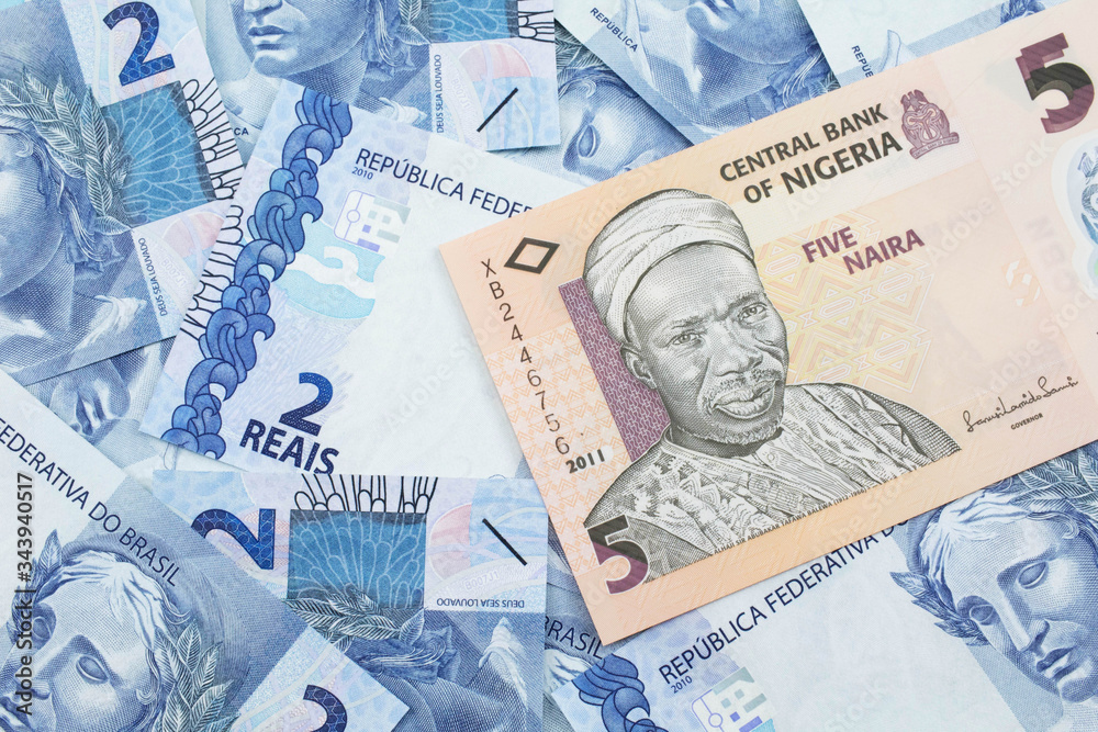 Fototapeta premium A close up image of a peach colored, five Nigerian naira bank note on a background of Brazilian two reais bank notes
