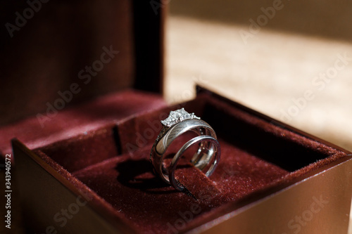 Wedding and engagement rings from white gold with gemstones shining in brown box. Brides and grooms jewelry close-up