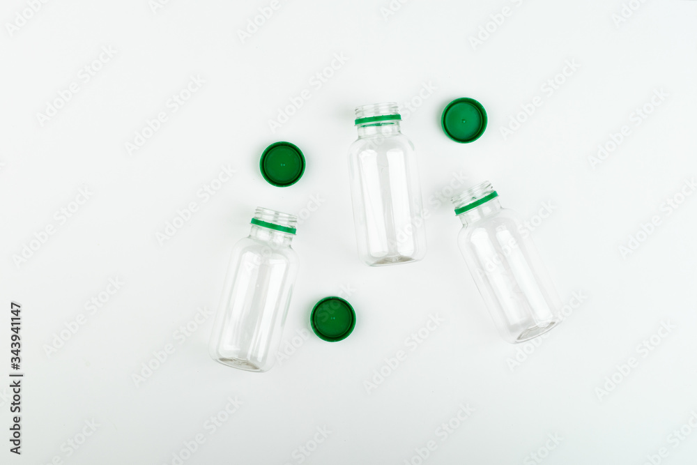 Three open empty transparent plastic jars with green caps on a white background, top view. 
