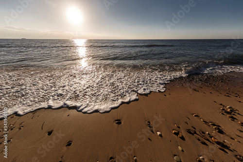 bagnasciuga in un spiaggia con risacca delle onde al tramonto photo