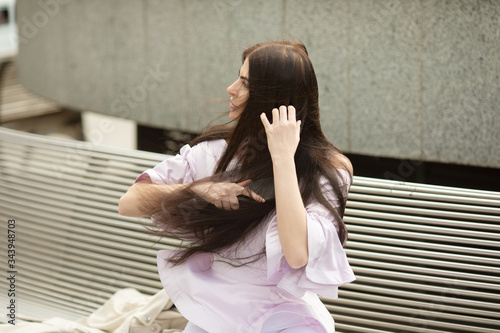 Beautiful woman combs long hair in the summer day.
