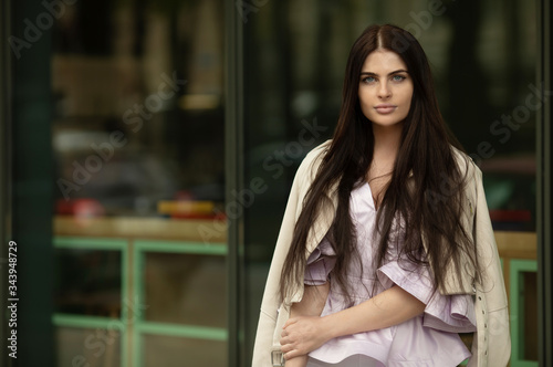 Fashion style portrait of young beautiful elegant brunette woman walking at city streets on a windy dull day.