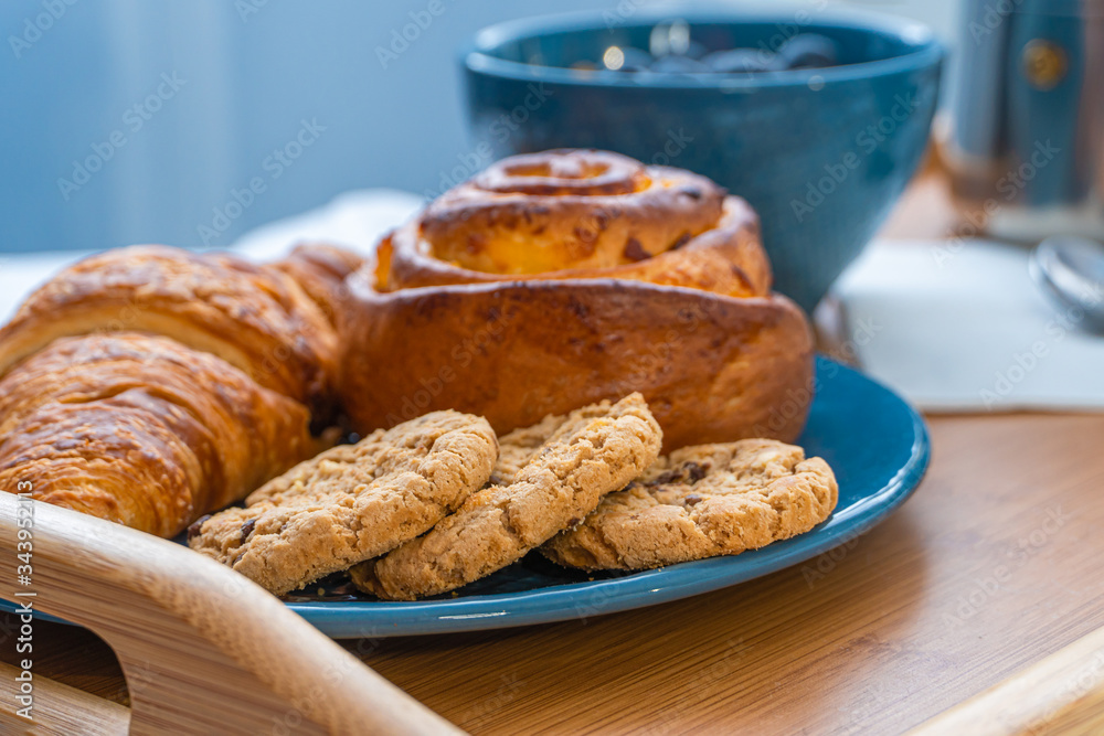 Breakfast served in bed on wooden tray with coffee and croissants Breakfast served in bed on wooden tray with coffee and croissants