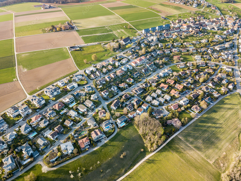 A cluster of houses in the suburban surrounding by fields by aerial drone photogrpaphy