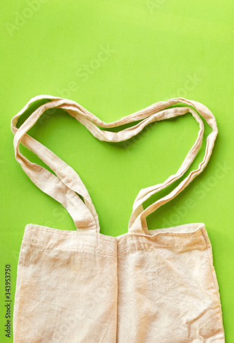 Heart shaped bag handles canvas fabric cloth eco shopping sack mockup blank template on green background . Protect earth concept