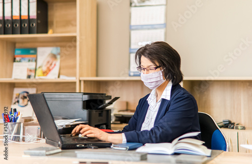 Woman in a mask working in the office - coronavirus time