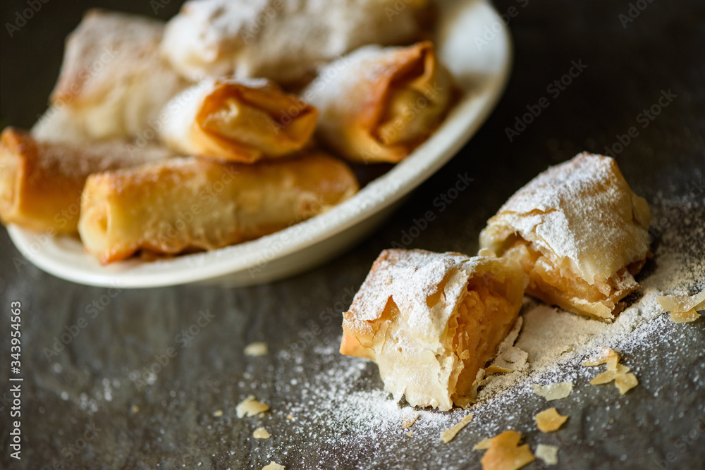 Apple rolls powdered with sugar arranged in a ceramic bowl . Apple rolls powdered with sugar arranged in a ceramic bowl .
