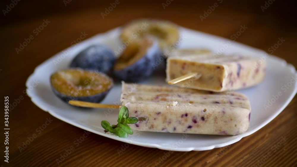 plum sweet homemade ice cream on a stick with slices of plum inside, in a plate