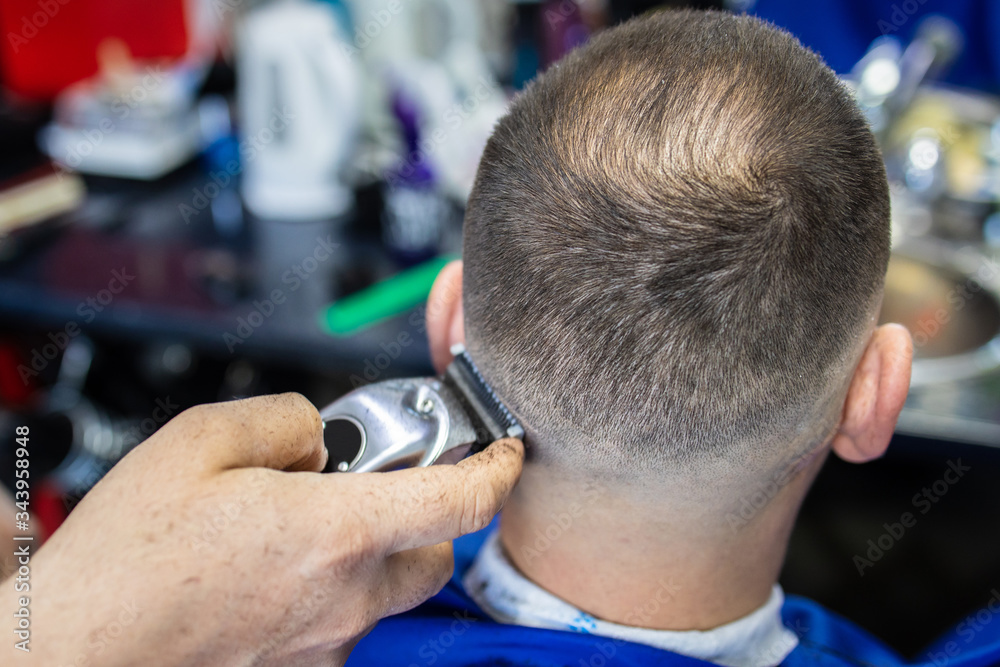 Close up shot of a man getting a trendy haircut at a hair salon. Male Bulgarian hairdresser serving a client. Master hairdresser making haircut with a typewriter. Close up shot of a man getting a trendy haircut at a hair salon. Male Bulgarian hairdresser serving a client. Master hairdresser making haircut with a typewriter.