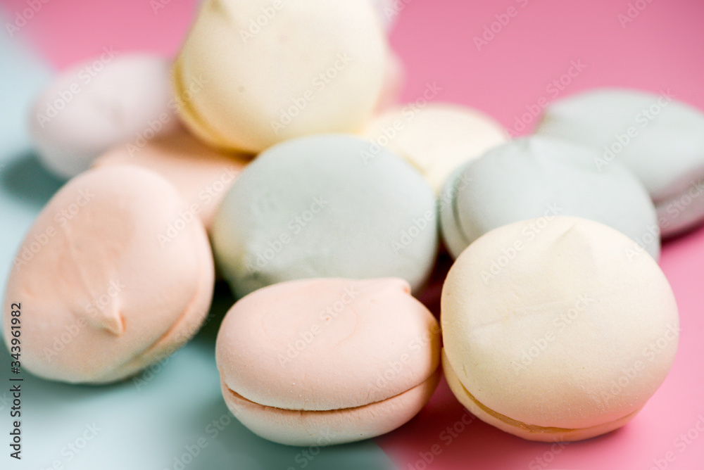 Colored sweet dessert zephyr marshmallows on pink & blue background. Air marshmallows. Close up, foo? photography Colored sweet dessert zephyr marshmallows on pink & blue background. Air marshmallows. Close up, foo? photography