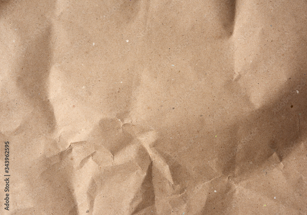 Naklejka premium crumpled blank sheet of brown wrapping kraft paper, vintage texture for the designer