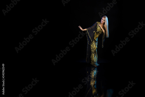 Young woman oriental dancer in national traditional Khaliji dress with feathers on a black background photo