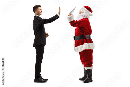 Young man in a black suit making high-five gesture with Santa Claus