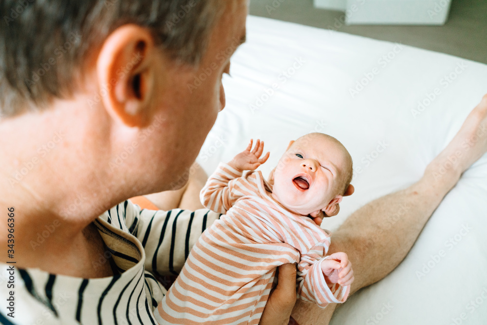 Closeup portrait of a newborn making a funny face while being held