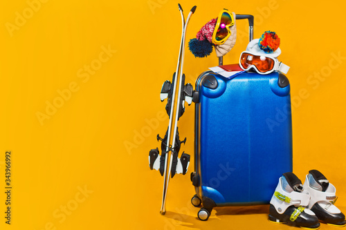 ski suitcase boots and accessories for a ski resort on a yellow background in the studio, winter vacations, active sport, place for text