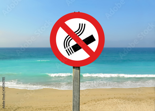 No smoking sign on the beach. Warning: smoke free zone. Tobacco and cigarettes are banned on beaches. Prohibition red sign. Beautiful spanish beach in background, Spain. 