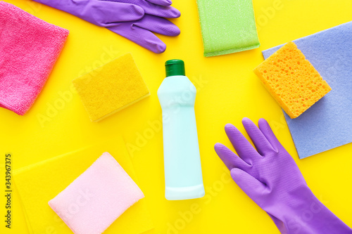 Colorful cleaning set for different surfaces in kitchen on yellow background. Top view, flat lay