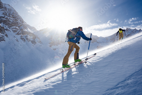 Man ski touring up hill in the wind and backlit by the sun