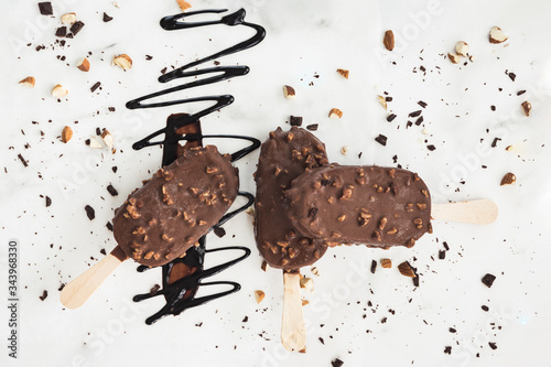 three ice cream bars on a white background, chocolate drizzle and nuts photo