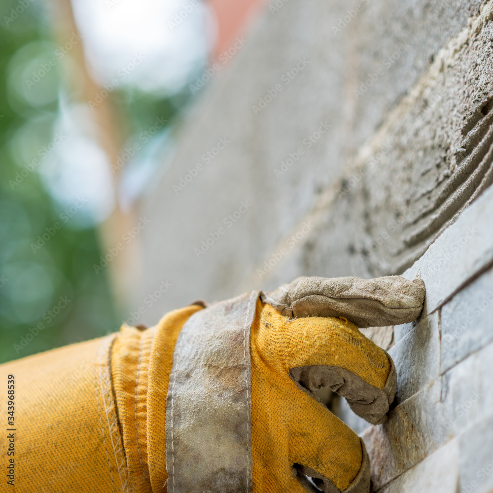 Pressing an ornamental tile into a glue on a wall Pressing an ornamental tile into a glue on a wall