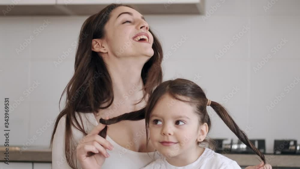 It is Mother's Day. The kid has given her mother flowers as a gift. The mother is cooking a breakfast. The child is drinking an orange juice. The mother and kid are having fun spending time together. It is Mother's Day. The kid has given her mother flowers as a gift. The mother is cooking a breakfast. The child is drinking an orange juice. The mother and kid are having fun spending time together.