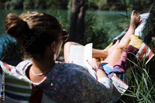 Woman with sunglasses reading a book lying on a hammock. photo