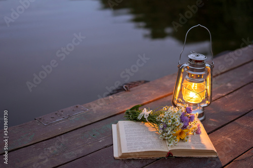 Vintage oil lamp on a wooden background on the background of the evening forest lake. photo